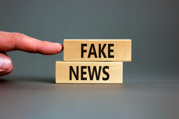 Fake news symbol. Wooden blocks with concept words Fake news on beautiful grey background. Businessman hand. Business media and fake news concept. Copy space.