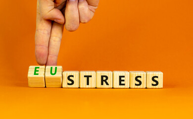 Eustress or stress symbol. Psychologist turns cubes and changes the concept word Eustress to Stress. Beautiful orange table orange background, copy space. Psychlogical stress or eustress concept.