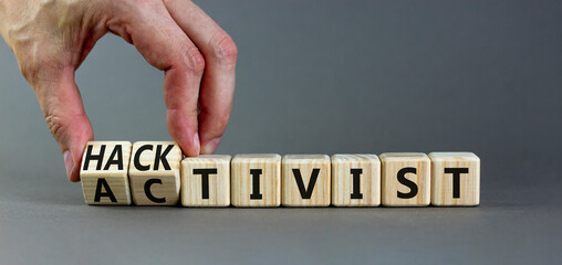 Activist or hacktivist symbol. Businessman turns wooden cubes and changes the word Activist to Hacktivist. Beautiful grey table grey background, copy space. Business activist or hacktivist concept.