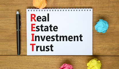 REIT real estate investment trust symbol. Concept words REIT real estate investment trust on the note on beautiful white background. Business REIT real estate investment trust concept.