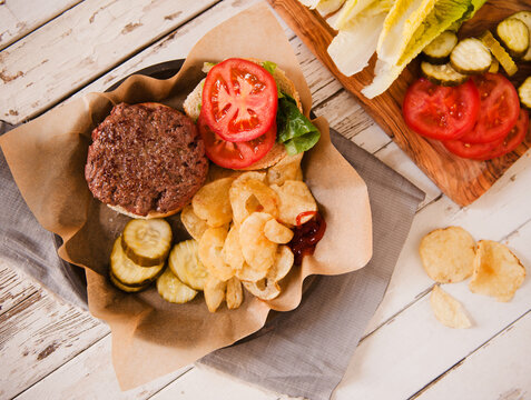 Hamburger with lettuce, tomato, pickles and potato chips