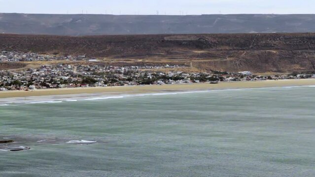 side detail panning of the mountains of Rada Tilly Patagonia Argentina where we see the mountains open the way to the city with the beach in the background during a sunny winter day