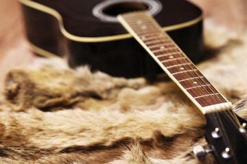 Old dusty acoustic cutaway guitar on a floor. Spruce dreadnought acoustic guitar. Guitar on a fur...