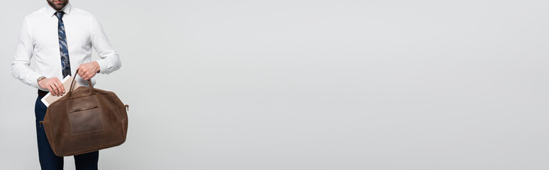 partial view of businessman taking folder out of briefcase isolated on grey, banner.