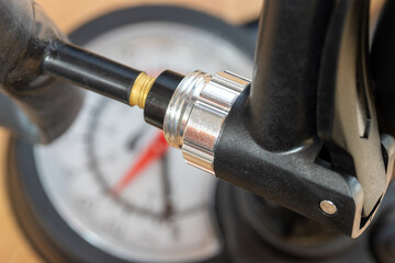 Close-up view of a pump with manometer blowing air into a valve of inner tube