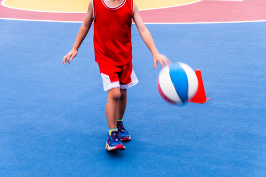 Unidentified kid dribbling and playing basketball in basketball court - Powered by Adobe