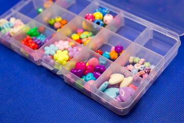 Colorful bright accessories needlework in a plastic box on a blue background.