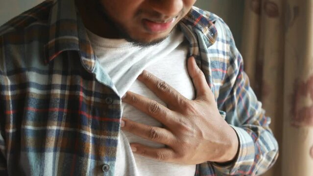 young man suffering pain in heart and holding chest with hand 