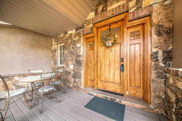 House entrance with chairs and table near the wooden front door