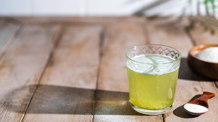 Collagen powder and glass of water on wooden background. Extra protein intake. Natural beauty and health supplement