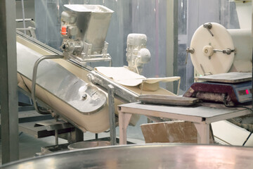 Belt conveyor for dough at a bakery factory. Bakery equipment for portioning and transporting dough. Motion-blurred pieces of equipment.