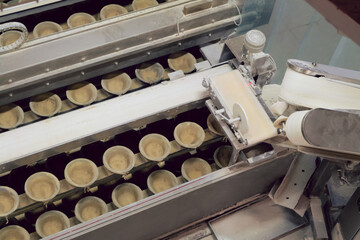 Bakery equipment for cutting, portioning and transporting dough. Conveyor with bowls for dough at a...