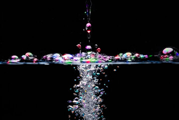 A heavy object dropped into clear water, creating many bubbles above and below the surface.  The bubbles have been coloured, for extra impact.