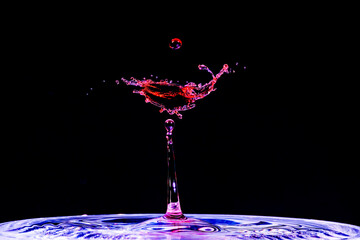 As red water dropped into blue water, the splash made a beautiful cocktail, complete with cherry.