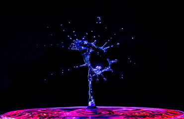 A blue water droplet splashing into red water, creating a beautiful alien shape.