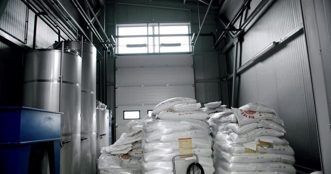 Production of beer with malt grains in the large mill in the brewery. Large beer grinder. Malt grains that are stored at the plant. Crushing malt. Malt bags.