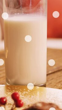Animation of white spots over milk and cookies at christmas