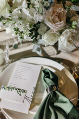 Banquet table is decorated with plates, cutlery, glasses, candles and flower arrangements. Wedding decor