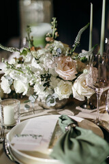 Banquet table is decorated with plates, cutlery, glasses, candles and flower arrangements. Wedding decor
