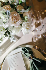 Banquet table is decorated with plates, cutlery, glasses, candles and flower arrangements. Wedding decor