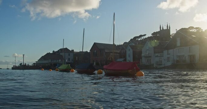 Sail Boats Floating in Fowey Harbour Beside Waterfront Homes in Evening Sunshine, Cornwall, England - Low angle
