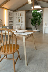 cozy warm home interior of a chic country house with an open plan, wood finishes, warm colors and a family hearth. view of the dining area, table and table setting