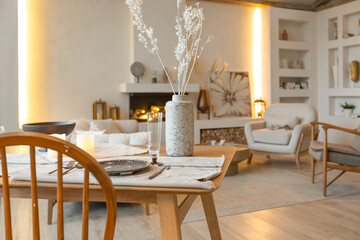 Fototapeta na wymiar cozy warm home interior of a chic country house with an open plan, wood finishes, warm colors and a family hearth. view of the dining area, table and table setting