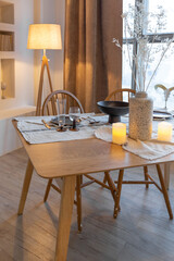 cozy warm home interior of a chic country chalet with a huge panoramic window overlooking the winter forest. open plan, wood decoration, warm colors and a family hearth