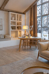 cozy warm home interior of a chic country chalet with a huge panoramic window overlooking the winter forest. open plan, wood decoration, warm colors and a family hearth