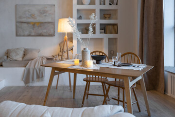 cozy warm home interior of a chic country house with an open plan, wood finishes, warm colors and a family hearth. view of the dining area, table and table setting