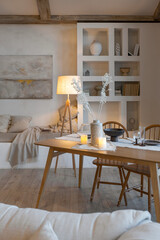 cozy warm home interior of a chic country house with an open plan, wood finishes, warm colors and a family hearth. view of the dining area, table and table setting