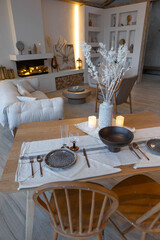 cozy warm home interior of a chic country house with an open plan, wood finishes, warm colors and a family hearth. view of the dining area, table and table setting