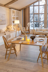 cozy warm home interior of a chic country chalet with a huge panoramic window overlooking the winter forest. open plan, wood decoration, warm colors and a family hearth