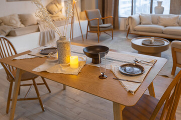 cozy warm home interior of a chic country house with an open plan, wood finishes, warm colors and a family hearth. view of the dining area, table and table setting