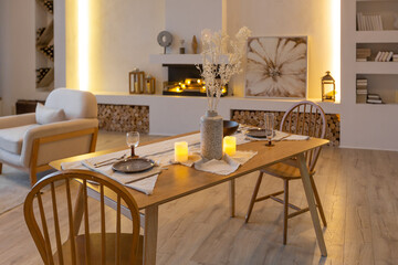 cozy warm home interior of a chic country house with an open plan, wood finishes, warm colors and a family hearth. view of the dining area, table and table setting