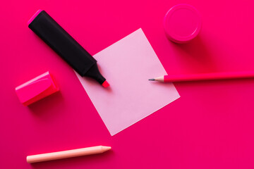 top view of stationery near jar with paint and blank paper note on pink.