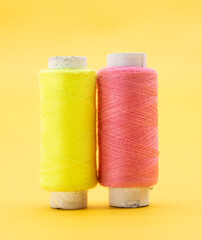 yellow and pink color yarn or spool thread over on yellow background