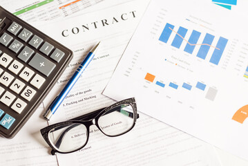 Contract, charts,pen, glasses and calculator at workplace