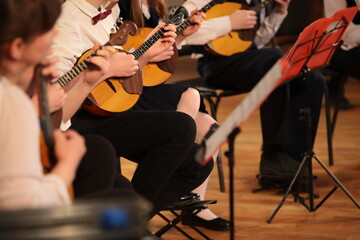 Balalaika in the hands of a young musician playing in an ensemble of stringed instruments the...