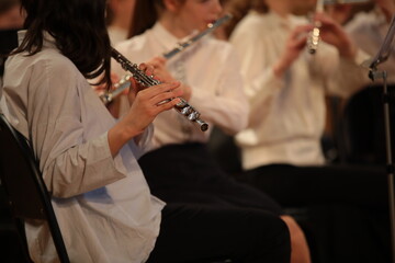 A woman with a flute playing in an orchestra