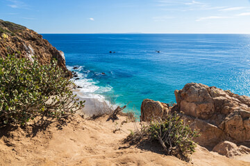 Fototapeta na wymiar View from the cliffs at Point Dume, Malibu, California. Plants and rocks in foreground. Pacific Ocean, sky and clouds in distance. 