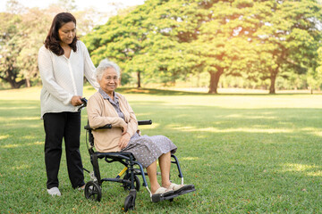 Caregiver help and care Asian senior or elderly old lady woman patient sitting on wheelchair in park, healthy strong medical concept.