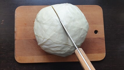 A knife cuts cabbage on a cutting board