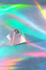 quartz crystal pyramid (triangle) on holographic background. Refracting vivid colors light. Magic...