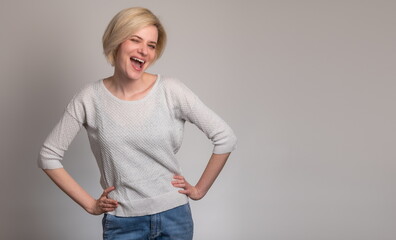 Smiling confidence. Beautiful young blonde women looking at camera and posing while standing against grey background winking looking at the camera with sexy expression, cheerful and happy face.