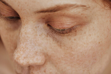 Obraz premium Macro shot of face with freckles of young natural woman with no-makeup on her eyes