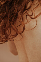 Rear view of young shirtless woman with long red curly hair