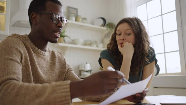 White woman looks at African American realtor telling details of apartment purchase. Man and female client sit at table discussing agreement closeup