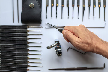 Many key picks in locksmith's hand are tools that require skill and practice to work in picking or...