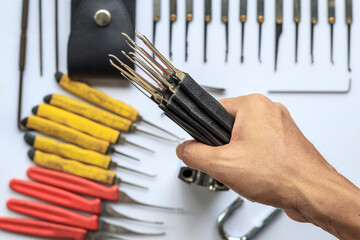 Many key picks in locksmith's hand are tools that require skill and practice to work in picking or...